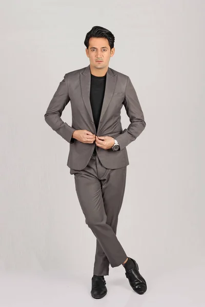 Takım elbiseli, siyah pantolonlu, beyaz arka planda izole edilmiş genç bir adamın tam boy portresi..