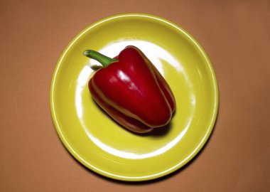 Kırmızı biber, bej arka planda sarı bir platel.