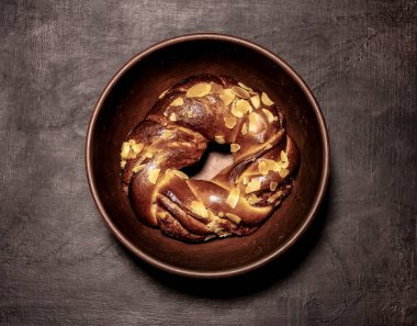 Tarçınlı çörek, arka planda kilden bir kasede fındıklı.