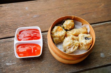 Mükemmel bir rahatlama anı için baharatlı acı biber soslu bambu sepetinde bir porsiyon sıcak dim sum..