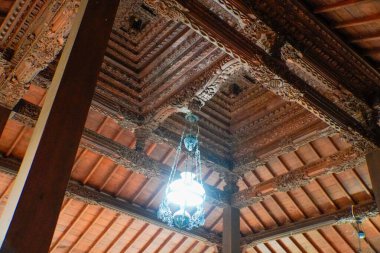 Geleneksel bir Cava yontulmuş ahşap avize oyulmuş ahşap çatı altında zengin kültürel mirası ve mimari ayrıntıları gözler önüne seriyor oyulmuş antik lambanın güzelliği