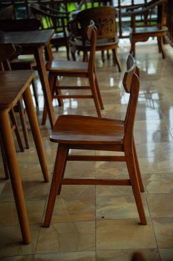 Kahverengi ahşap masa ve sandalyeler gölgeli kafeterya terasında..