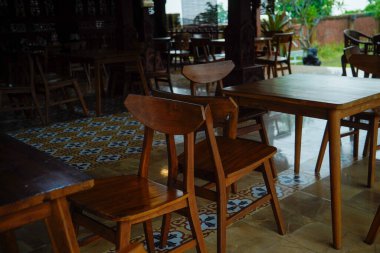 Kahverengi ahşap masa ve sandalyeler gölgeli kafeterya terasında..