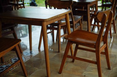 Kahverengi ahşap masa ve sandalyeler gölgeli kafeterya terasında..