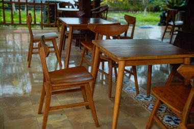 Kahverengi ahşap masa ve sandalyeler gölgeli kafeterya terasında..