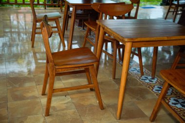 Kahverengi ahşap masa ve sandalyeler gölgeli kafeterya terasında..