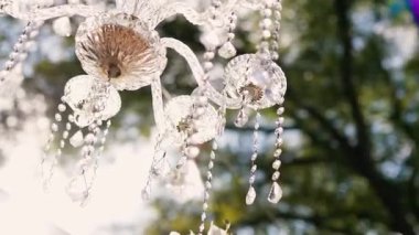 Cam bir avize ve güneş ışığında parlayan kristal bir avize. Güzel yansımalar ve ışınlar, bir ışık oyunu. Tören için düğün kemeri dekoru..