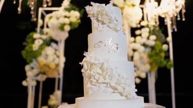 Akşam düğün kemeri beyaz çiçekler ve açık havada fenerlerle yeşillik. Resmî törende çiçek ve dekor. Kremalı büyük beyaz pasta.