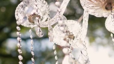 Cam bir avize ve güneş ışığında parlayan kristal bir avize. Güzel yansımalar ve ışınlar, bir ışık oyunu. Tören için düğün kemeri dekoru..