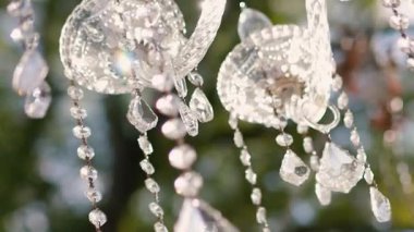 Cam bir avize ve güneş ışığında parlayan kristal bir avize. Güzel yansımalar ve ışınlar, bir ışık oyunu. Tören için düğün kemeri dekoru.