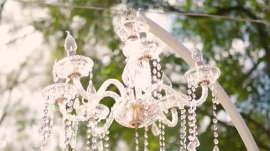 Cam bir avize ve güneş ışığında parlayan kristal bir avize. Güzel yansımalar ve ışınlar, bir ışık oyunu. Tören için düğün kemeri dekoru.