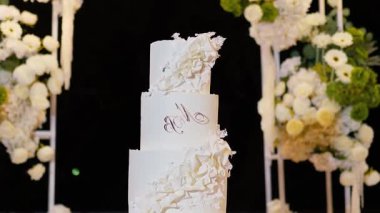 Akşam düğün kemeri beyaz çiçekler ve açık havada fenerlerle yeşillik. Resmî törende çiçek ve dekor. Kremalı büyük beyaz pasta.