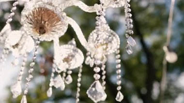 Cam bir avize ve güneş ışığında parlayan kristal bir avize. Güzel yansımalar ve ışınlar, bir ışık oyunu. Tören için düğün kemeri dekoru.