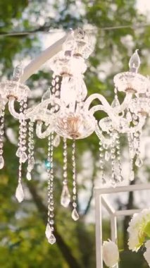 Cam bir avize ve güneş ışığında parlayan kristal bir avize. Güzel yansımalar ve ışınlar, bir ışık oyunu. Tören için düğün kemeri dekoru.