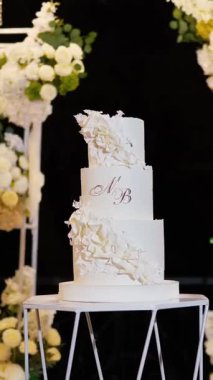 Akşam düğün kemeri beyaz çiçekler ve açık havada fenerlerle yeşillik. Resmî törende çiçek ve dekor. Kremalı büyük beyaz pasta.