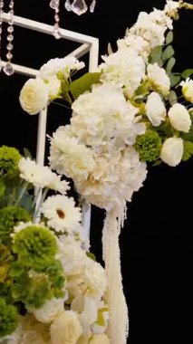 Akşam düğün kemeri beyaz çiçekler ve açık havada fenerlerle yeşillik. Resmî törende çiçek ve dekor. Kremalı büyük beyaz pasta.