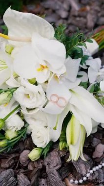 Düğünden önceki gün, güzel ve güzel kokulu bir buket beyaz gül ve zambak. Aşkın sembolü olarak alyansların yakın plan çekimi..