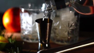 Cin tonik ve bardaklarda buzla yapılan nefis alkollü kokteyl geceleri dinlenmek ve yazın ferahlatıcı olmak için. Baharat ve aroma için yeşil limon. Barmen ve bar. Biberiye ateşle yanıyor.