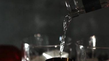 Cin tonik ve bardaklarda buzla yapılan nefis alkollü kokteyl geceleri dinlenmek ve yazın ferahlatıcı olmak için. Baharat ve aroma için yeşil limon. Barmen ve bar. Biberiye ateşle yanıyor.