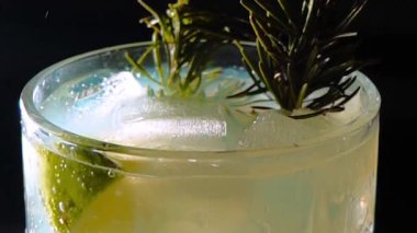 Cin tonik ve bardaklarda buzla yapılan nefis alkollü kokteyl geceleri dinlenmek ve yazın ferahlatıcı olmak için. Baharat ve aroma için yeşil limon. Barmen ve bar. Biberiye ateşle yanıyor.