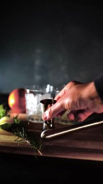Cin tonik ve bardaklarda buzla yapılan nefis alkollü kokteyl geceleri dinlenmek ve yazın ferahlatıcı olmak için. Baharat ve aroma için yeşil limon. Barmen ve bar. Biberiye ateşle yanıyor.