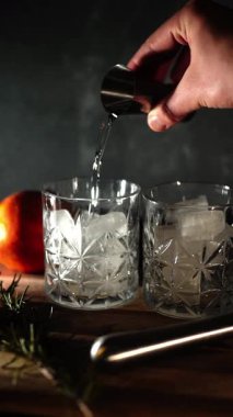Cin tonik ve bardaklarda buzla yapılan nefis alkollü kokteyl geceleri dinlenmek ve yazın ferahlatıcı olmak için. Baharat ve aroma için yeşil limon. Barmen ve bar. Biberiye ateşle yanıyor.