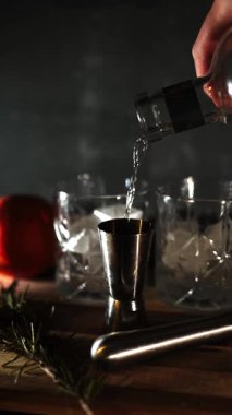 Cin tonik ve bardaklarda buzla yapılan nefis alkollü kokteyl geceleri dinlenmek ve yazın ferahlatıcı olmak için. Baharat ve aroma için yeşil limon. Barmen ve bar. Biberiye ateşle yanıyor.