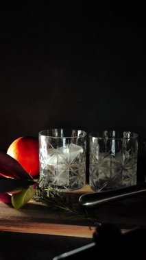 Cin tonik ve bardaklarda buzla yapılan nefis alkollü kokteyl geceleri dinlenmek ve yazın ferahlatıcı olmak için. Baharat ve aroma için yeşil limon. Barmen ve bar. Biberiye ateşle yanıyor.