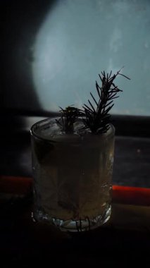 Cin tonik ve bardaklarda buzla yapılan nefis alkollü kokteyl geceleri dinlenmek ve yazın ferahlatıcı olmak için. Baharat ve aroma için yeşil limon. Barmen ve bar. Biberiye ateşle yanıyor.