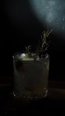 Cin tonik ve bardaklarda buzla yapılan nefis alkollü kokteyl geceleri dinlenmek ve yazın ferahlatıcı olmak için. Baharat ve aroma için yeşil limon. Barmen ve bar. Biberiye ateşle yanıyor.