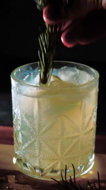 Cin tonik ve bardaklarda buzla yapılan nefis alkollü kokteyl geceleri dinlenmek ve yazın ferahlatıcı olmak için. Baharat ve aroma için yeşil limon. Barmen ve bar. Biberiye ateşle yanıyor.