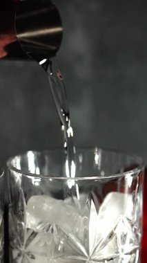 Cin tonik ve bardaklarda buzla yapılan nefis alkollü kokteyl geceleri dinlenmek ve yazın ferahlatıcı olmak için. Baharat ve aroma için yeşil limon. Barmen ve bar. Biberiye ateşle yanıyor.