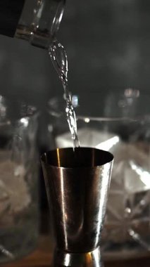 Cin tonik ve bardaklarda buzla yapılan nefis alkollü kokteyl geceleri dinlenmek ve yazın ferahlatıcı olmak için. Baharat ve aroma için yeşil limon. Barmen ve bar. Biberiye ateşle yanıyor.