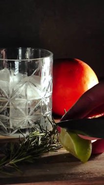 Cin tonik ve bardaklarda buzla yapılan nefis alkollü kokteyl geceleri dinlenmek ve yazın ferahlatıcı olmak için. Baharat ve aroma için yeşil limon. Barmen ve bar. Biberiye ateşle yanıyor.