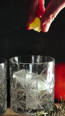 Cin tonik ve bardaklarda buzla yapılan nefis alkollü kokteyl geceleri dinlenmek ve yazın ferahlatıcı olmak için. Baharat ve aroma için yeşil limon. Barmen ve bar. Biberiye ateşle yanıyor.