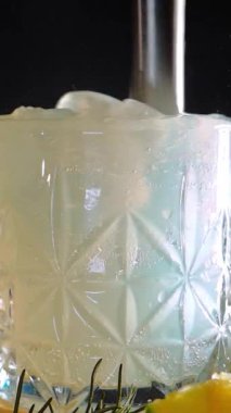 Cin tonik ve bardaklarda buzla yapılan nefis alkollü kokteyl geceleri dinlenmek ve yazın ferahlatıcı olmak için. Baharat ve aroma için yeşil limon. Barmen ve bar. Biberiye ateşle yanıyor.