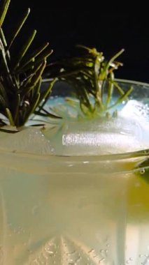 Cin tonik ve bardaklarda buzla yapılan nefis alkollü kokteyl geceleri dinlenmek ve yazın ferahlatıcı olmak için. Baharat ve aroma için yeşil limon. Barmen ve bar. Biberiye ateşle yanıyor.