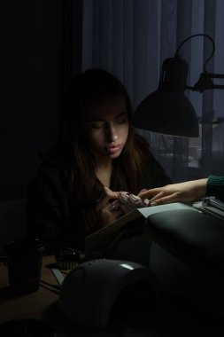 Güzellik ustası manikürcü, güzellik salonunda genç ve güzel bir kıza el ve parmaklarıyla manikür yapıyor. Tamirci aletlerini kapat