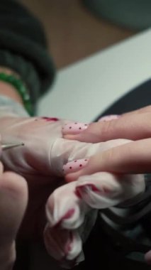 Güzellik ustası manikürcü, güzellik salonunda genç ve güzel bir kıza el ve parmaklarıyla manikür yapıyor. Tamirci aletlerini kapat