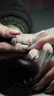 Güzellik ustası manikürcü, güzellik salonunda genç ve güzel bir kıza el ve parmaklarıyla manikür yapıyor. Tamirci aletlerini kapat