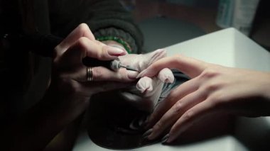 Güzellik ustası manikürcü, güzellik salonunda genç ve güzel bir kıza el ve parmaklarıyla manikür yapıyor. Tamirci aletlerini kapat