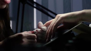 Güzellik ustası manikürcü, güzellik salonunda genç ve güzel bir kıza el ve parmaklarıyla manikür yapıyor. Tamirci aletlerini kapat