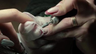 Güzellik ustası manikürcü, güzellik salonunda genç ve güzel bir kıza el ve parmaklarıyla manikür yapıyor. Tamirci aletlerini kapat