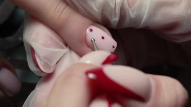 Güzellik ustası manikürcü, güzellik salonunda genç ve güzel bir kıza el ve parmaklarıyla manikür yapıyor. Tamirci aletlerini kapat