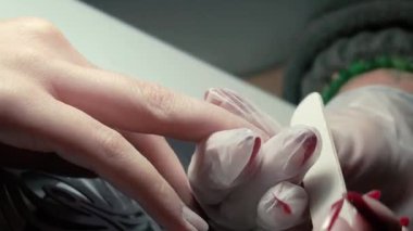 Güzellik ustası manikürcü, güzellik salonunda genç ve güzel bir kıza el ve parmaklarıyla manikür yapıyor. Tamirci aletlerini kapat