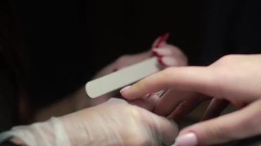 Güzellik ustası manikürcü, güzellik salonunda genç ve güzel bir kıza el ve parmaklarıyla manikür yapıyor. Tamirci aletlerini kapat