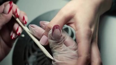 Güzellik ustası manikürcü, güzellik salonunda genç ve güzel bir kıza el ve parmaklarıyla manikür yapıyor. Tamirci aletlerini kapat