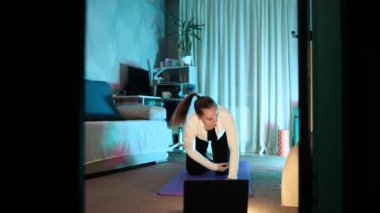 Genç bir kız, güzel bir kadın evde yoga yapıyor. Kas tonlama, vücut esneme ve meditasyon egzersizleri. Özbakım, güzellik, gençlik ve sağlık. Spor ve ısınma egzersizleri..