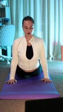 Genç bir kız, güzel bir kadın evde yoga yapıyor. Kas tonlama, vücut esneme ve meditasyon egzersizleri. Özbakım, güzellik, gençlik ve sağlık. Spor ve ısınma egzersizleri..