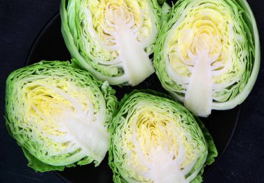 Siyah arka planda siyah bir tabakta lahana ikiye bölünmüş. Üst görünüm.